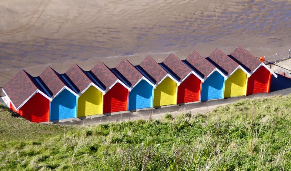 Scarborough, England. Row of colorful beach chalets by seaside. #travel #Scarborough www.road-ventures.com